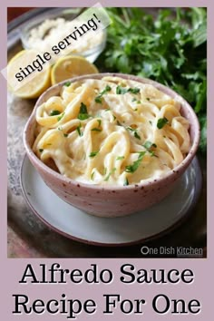 a bowl of alfredo sauce on a plate with lemons and parsley