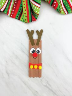 a craft made out of pops sticks with reindeer's head on it, sitting on top of a white marble surface