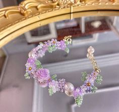 a close up of a necklace with flowers and pearls on it in front of a mirror