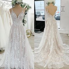 the back of a wedding dress with white flowers on it and in front of a mirror