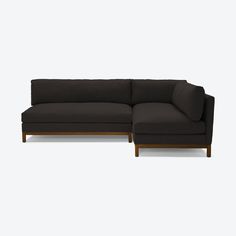 a black sectional couch sitting on top of a white floor next to a wooden frame