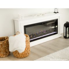 a white fireplace with two baskets on the floor next to it and an open fire place