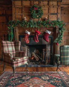 a living room with christmas stockings hanging on the fireplace and two chairs in front of it