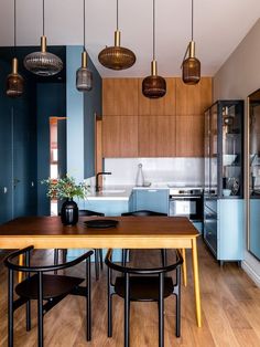 a kitchen with blue walls and wooden floors is seen in this image from the dining room