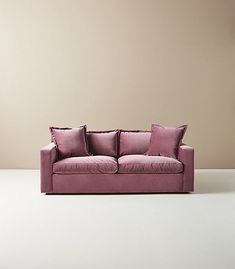 a pink couch sitting on top of a white floor next to a brown and beige wall