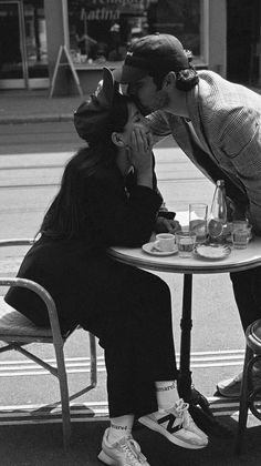 two people sitting at a table kissing each other