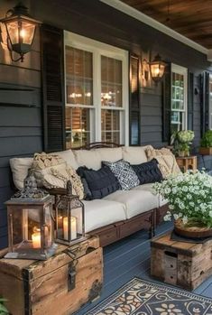 an outdoor living area with couches, coffee table and lanterns on the front porch