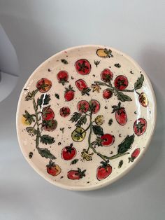 a white plate with red and green designs on it, sitting on a table top