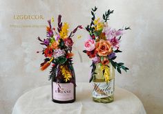 two vases filled with flowers sitting on top of a white cloth covered round table