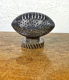 a metal football sitting on top of a wooden table next to a white brick wall