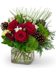 a vase filled with red roses and greenery