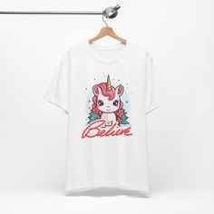 Matching child/kids sizes available here: https://www.etsy.com/listing/1611813227/kids-unicorn-christmas-t-shirt-color "Believe" cute Christmas unicorn is available in t-shirt color options including White, Heather Mauve, Olive, Heather Kelly, Dark Grey Heather, Heather Navy, Berry Pink, and Heather Red. It is adorned with white script hand lettering, and a super cute unicorn. This festive holiday top is perfect for parties, holiday travel, office gift exchanges, and all-around merriment in styl Christmas Believe, Unicorn Christmas, Christmas In The City, Christmas Unicorn, White Heather, Cartoon Gift, Holiday Tops, She Girl, Travel Office