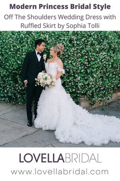 a bride and groom standing next to each other in front of a wall with flowers