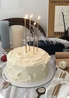 a white cake with five candles on it sitting on a table next to other items