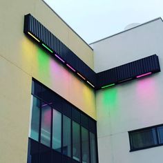 a building with multicolored lights on the side of it's roof and windows