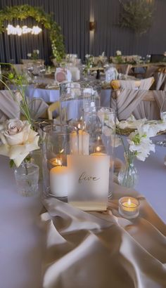 a table topped with lots of candles and vases filled with flowers on top of it