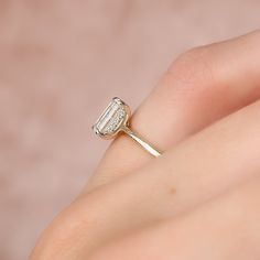 a woman's hand with a diamond ring on top of her finger, showing the side view