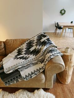 a couch with a blanket on top of it in a living room next to a table