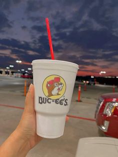 a person holding up a cup with a straw in it and the sky behind them