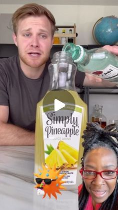 a man and woman sitting next to each other holding up bottles of pineapple juice