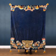 a leopard head on a blue velvet blanket with tassels and pom poms