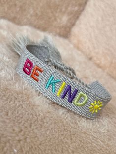 a bracelet with the word be kind on it sitting on top of a furry surface