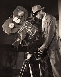 a man standing next to a camera on top of a tripod