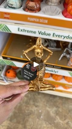 a person holding up a gold statue in front of some shelves filled with oranges