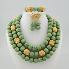 a necklace and earring set made out of green, yellow and white beads on a mannequin