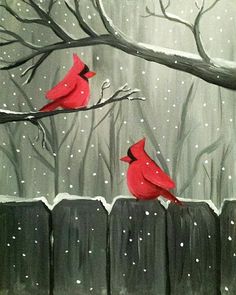 two red birds sitting on top of a tree branch in front of a snow covered forest