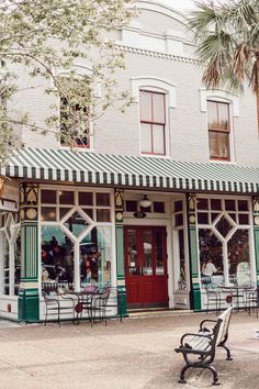 a bench sitting in front of a building with green and white striped awnings