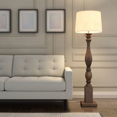 a white couch sitting next to a lamp on top of a hard wood floor in a living room