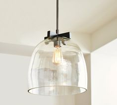 a clear glass light fixture hanging from a ceiling in a room with white walls and ceilings