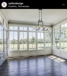 an empty room with large windows and wood flooring on the sides, along with a chandelier hanging from the ceiling