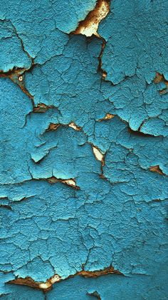 an old blue painted wall with peeling paint and chipped paint on the surface is seen in this image