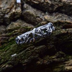 a silver ring sitting on top of a mossy rock covered in ligning