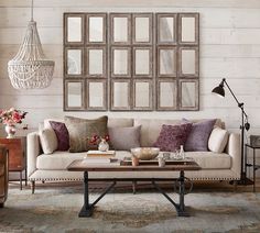 a living room filled with lots of furniture next to a wall covered in pictures and windows