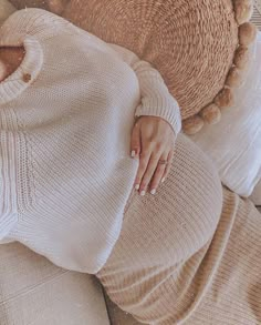 a woman laying on top of a couch next to a teddy bear wearing a sweater