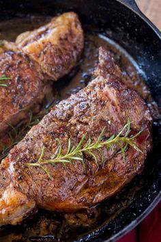 two steaks in a skillet with rosemary sprigs on the top and bottom