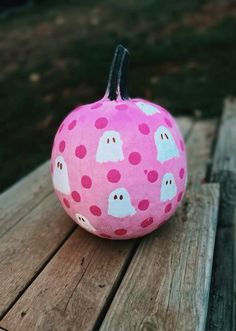 a pink painted pumpkin with ghost faces on it