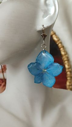 a close up of a person's head wearing earrings with blue flowers on them