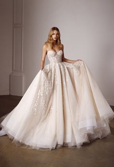 a woman in a wedding dress posing for the camera with her hands on her hips