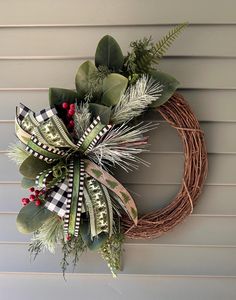 a christmas wreath hanging on the side of a house with greenery and berries attached to it