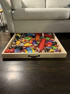 a living room filled with lots of toys on top of a wooden floor next to a couch