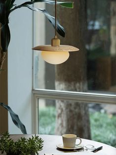 a table with a cup and saucer on it next to a potted plant