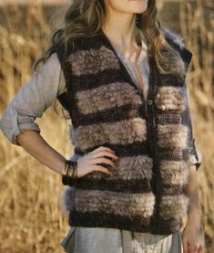 a woman standing in front of tall grass wearing a brown and black knitted vest