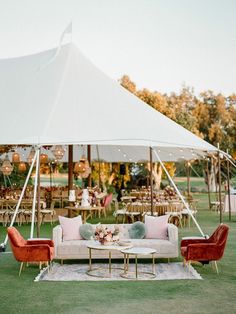 a tent set up with couches, chairs and tables