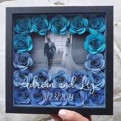 a person holding up a frame made out of paper flowers with the words, adam and lily on it