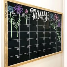 a chalk board with flowers drawn on it and the word may written in cursive writing