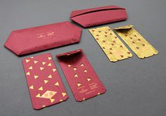 an assortment of red and gold items on a gray surface with one piece cut out